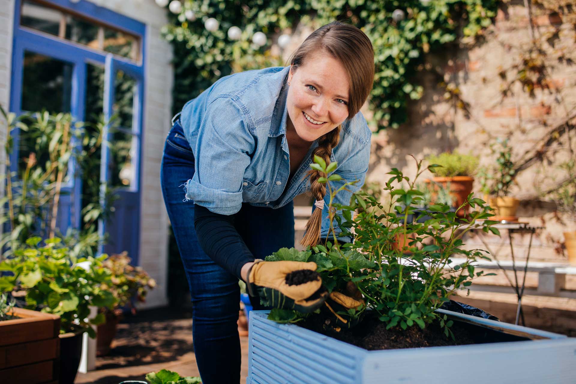 Pflanztröge und Blumentröge - Ambiente für Ihren Garten Junge Frau bepflanzt Pflanzkübel