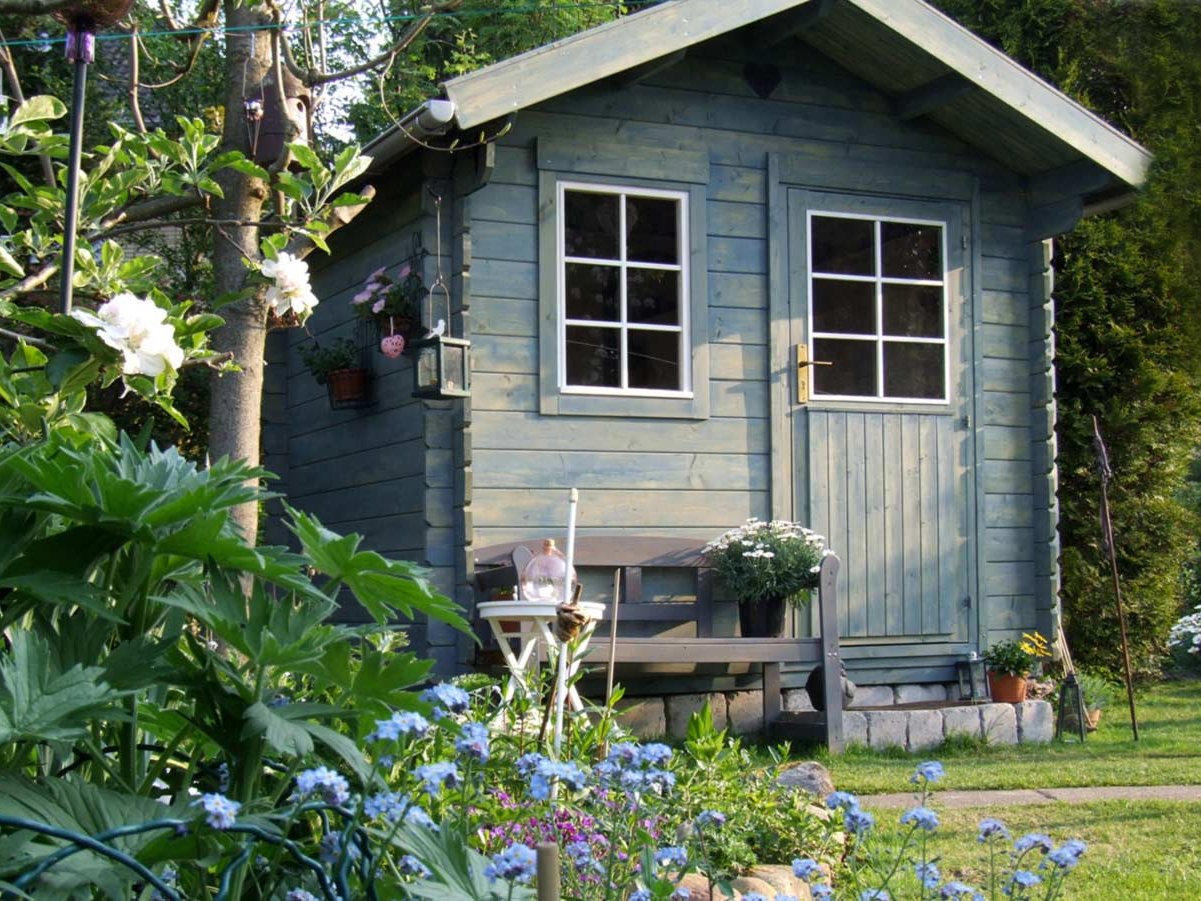 ein blaues Gartenhaus in einem saftigen grünen Garten