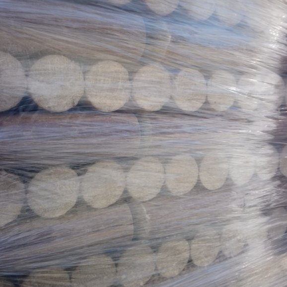 Seitlich fotografierte Palette mit runden Holzbriketts, sauber gestapelt und in Folie eingeschweißt