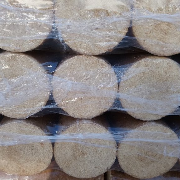 Frontalansicht auf die Stirnseiten runder Holzbriketts, sauber gestapelt und in Folie eingeschweißt